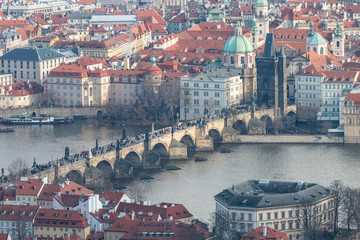 View of Charles Bridge, Old Town Bridge Tower and Church of St. Francis of Assisi. Beautiful Prague cityscape with classic red roofs, Vltava river and famous Czech showplaces.