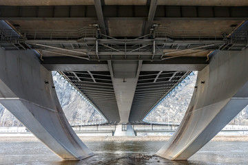 Bottom view of the large concrete highway bridge across the river.