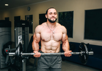 Fototapeta na wymiar Bearded man is training in the gym with weights. Handsome guy is doing exercises for good muscles. Fitness personal trainer is at work. Sport motivation healthy lifestyle. Fit bodybuilder.