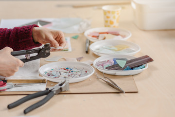 Obraz na płótnie Canvas Female hand cutting material on small pieces for mosaic