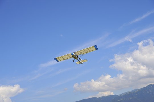 Aereo ultraleggero in volo dopo il decollo con cielo azzurro e nuvole bianche