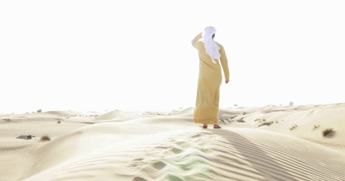 Arabian man with traditional emirates clothes walking on the Dubai desert. Different poses and expressions. Wearing yellow kandura 
