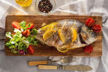 Grilled Dorado with lemon, cherry and fresh salad, top view