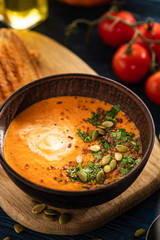 Pumpkin soup with sour cream and pumpkin seeds on a wooden table.