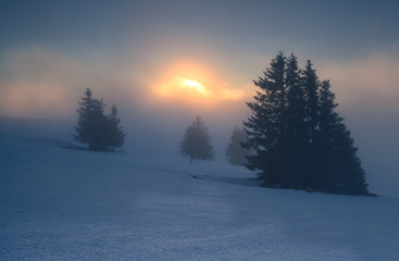 foggy sunrise on snowy mountain top