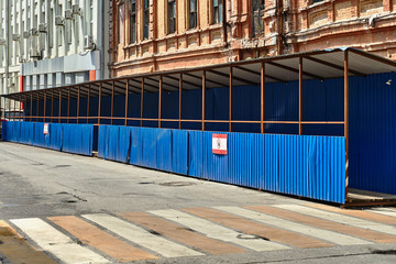 pedestrian crossing with a canopy of corrugated metal blue sheet metal and dervish flooring along the construction site with a dangerous zone