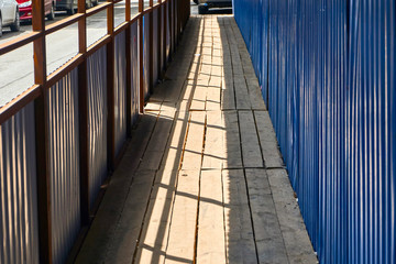 pedestrian crossing with a canopy of corrugated metal blue sheet metal and dervish flooring along the construction site with a dangerous zone