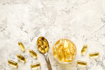 Fototapeta Bunch of omega 3 fish liver oil capsules in silver spoon. Close up of big golden translucent pills in pile. Healthy every day fatty acids nutritional supplement dosage. Top view, flat lay, copy space. obraz