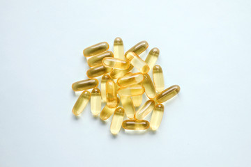 Bunch of omega 3 fish liver oil capsules in pile forming pattern background. Close up of big golden...