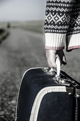 Ethnic refugee girl walking with her suitcase down the road