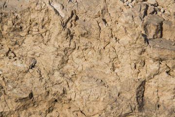 The texture of the stone wall of the rock with multi-colored shades, cracks, chips, scratches and small stones.