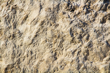 The texture of the stone wall of the rock with multi-colored shades, cracks, chips, scratches and small stones.