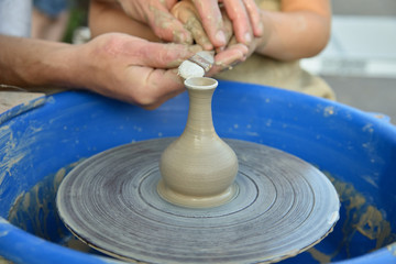 the master of pottery is teaching the child the craft