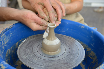 the master of pottery is teaching the child the craft