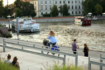 Dziewczyna, biznesmen jedzie na rowerze wzdłuż rzeki i rozmawia przez telefon.
