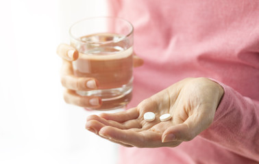 Tablets. A woman holds a pills and a glass of water. Close-up. Medical preparations. 