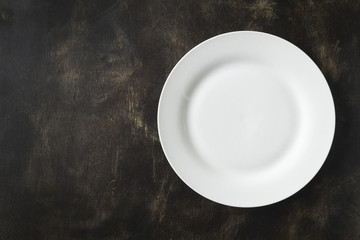 White empty plate on a black background. Free space for an inscription.