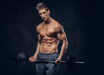 Fototapeta na wymiar Handsome shirtless man with stylish hair and muscular ectomorph doing the exercises with the barbell.
