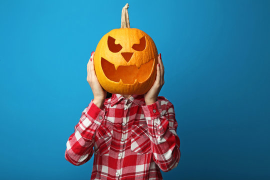 Female hands holding halloween pumpkin on blue background