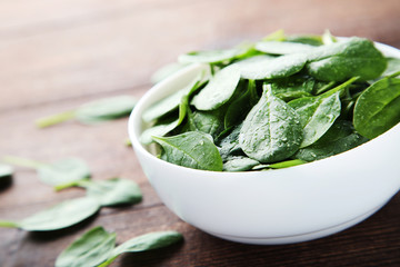 Spinach leafs in bowl on brown wooden table