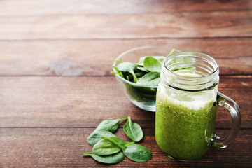 Spinach smoothie in glass jar on brown wooden table