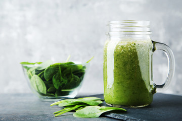 Spinach smoothie in glass jar on grey wooden table