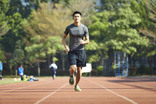 Young Asian Male Athlete Running On Track