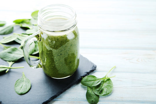 Spinach smoothie in glass jar on wooden table