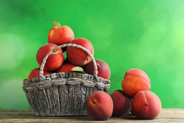 Sweet nectarines in basket on grey wooden table