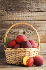 Sweet nectarines in basket on grey wooden table