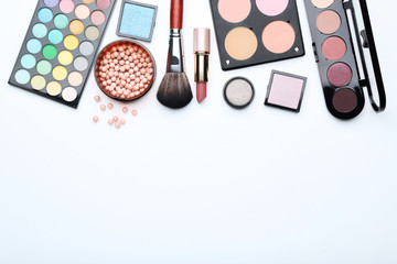 Makeup brush and different cosmetics on white background