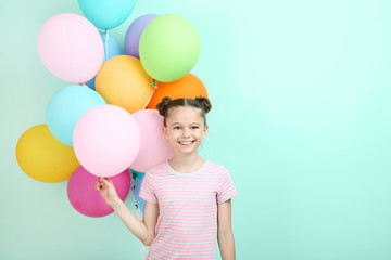 Beautiful young girl with colored balloons on mint background