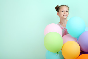 Beautiful young girl with colored balloons on mint background