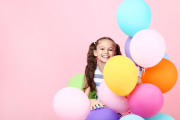 Fototapeta na wymiar Young girl with colored balloons on pink background