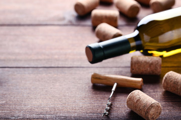 Fototapeta na wymiar Wine bottle with corks and corkscrew on brown wooden table