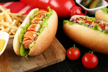 Hot dogs with ketchup, mustard and vegetables on wooden table