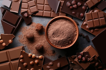 Chocolate pieces with cocoa powder in bowl and balls on wooden table