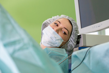 female surgeon doctor or intern wearing protective mask and hat.