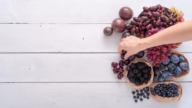 Selection of colorful fruits on white wooden table. 4k stop motion animation - flat lay - top down