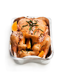 Raw whole duck with spices and oranges in a roasting oventray isolated on white. Ready for cooking.