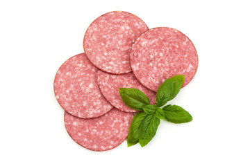 Dry salami sausage slices with basil leaves, isolated on white background. Top view.