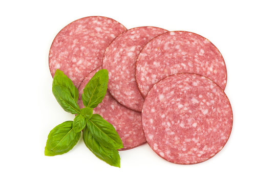 Dry salami sausage slices with basil leaves, isolated on white background. Top view.