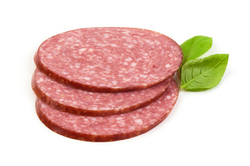Dry salami sausage slices with basil leaves, isolated on white background.