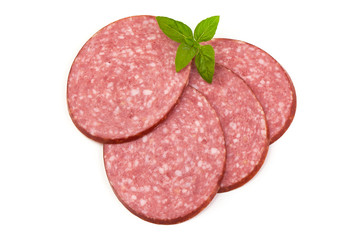 Dry salami sausage slices with basil leaves, isolated on white background. Top view.
