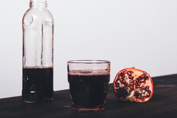 Glass of fresh made pomegranate juice near bottle