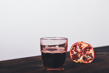 Glass of fresh made pomegranate juice next to half of garnet