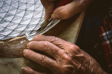 Hands of elderly man working the art of intarsia