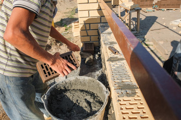 a worker at a construction site puts a brick