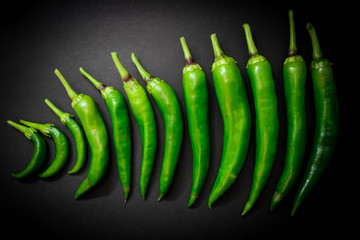 Several pods of hot green pepper on a black background