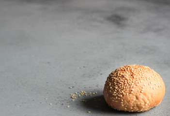 Fresh homemade burger buns with sesame seeds on grey concrete background. Concept of burger and homemade food. Dinner bread rolls or mini challah.